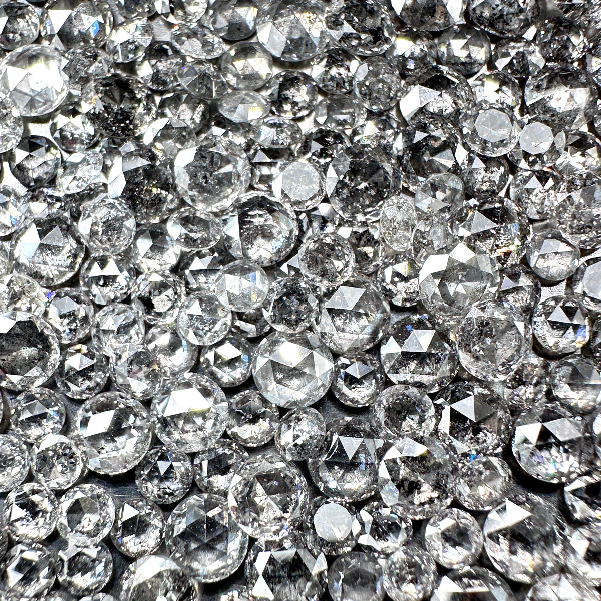 Collection of sparkling, rose-cut salt and pepper diamond melee stones with unique grey and black inclusions.